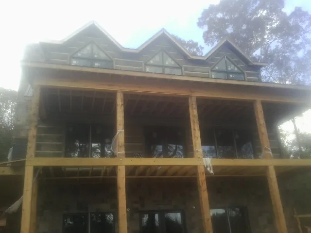 Dormers and porch framing on a large log home under construction — Roof Coating work by our crew in Minden
