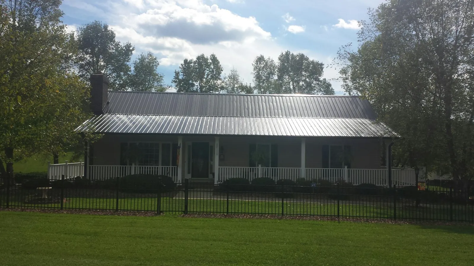 Gray metal roof on a brick ranch with a full width front porch — Gutter Guard Installation work by our crew in Minden