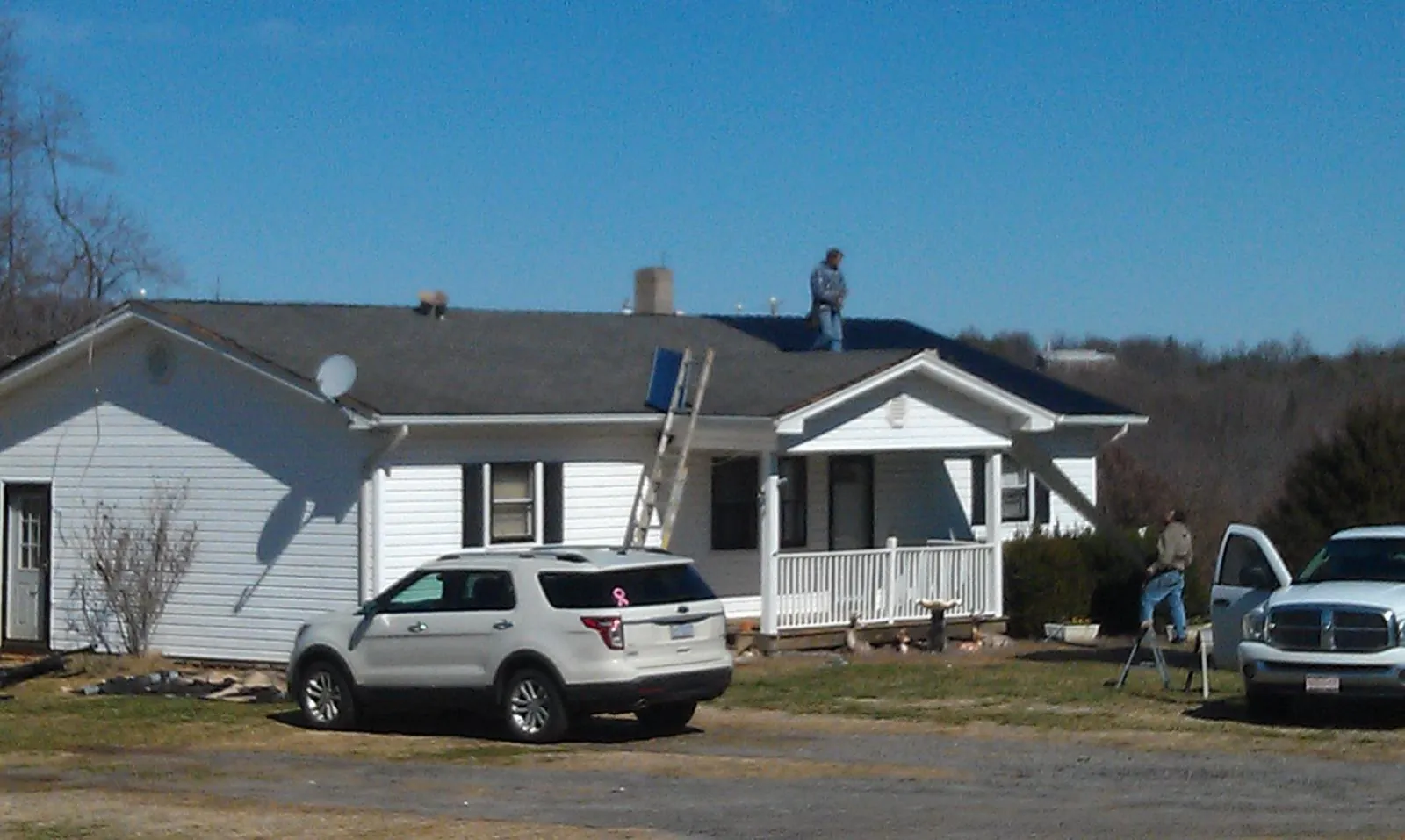 Roofers stripping shingles from a white ranch house roof in Minden